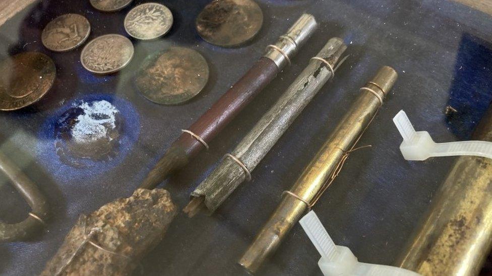 Display case containing coins and a pencil, among other items found with L/Sgt Charles Stevens