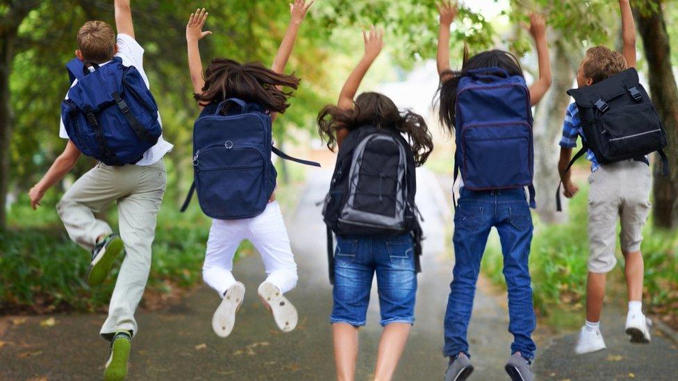 children with backpacks jumping