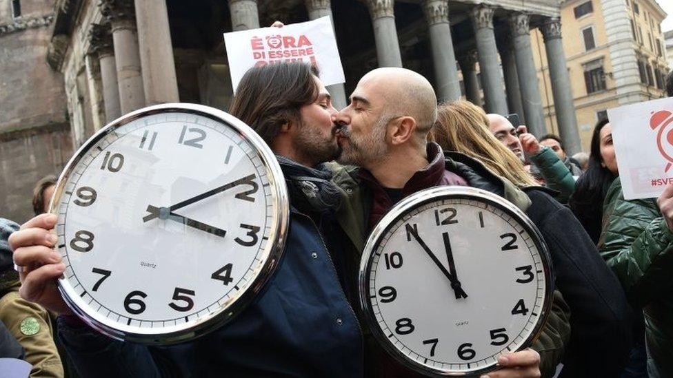 A couple holding alarm clocks kiss in Rome. Photo: January 2016