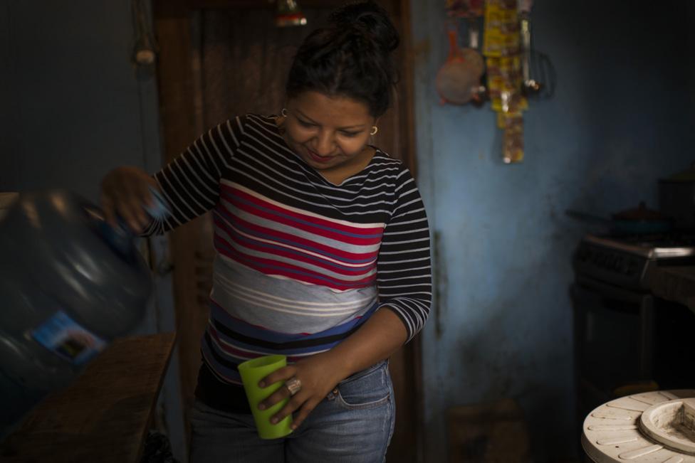 Sirly pours a glass of water in her grandmother's home