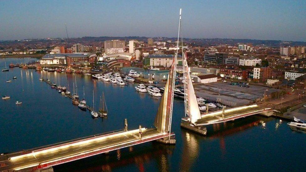 Poole's Twin sails bridge in the raised position - lit with gold and red lighting at dusk