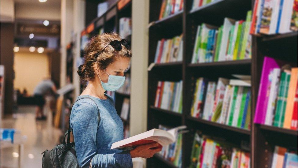 A student wearing a mask in a library