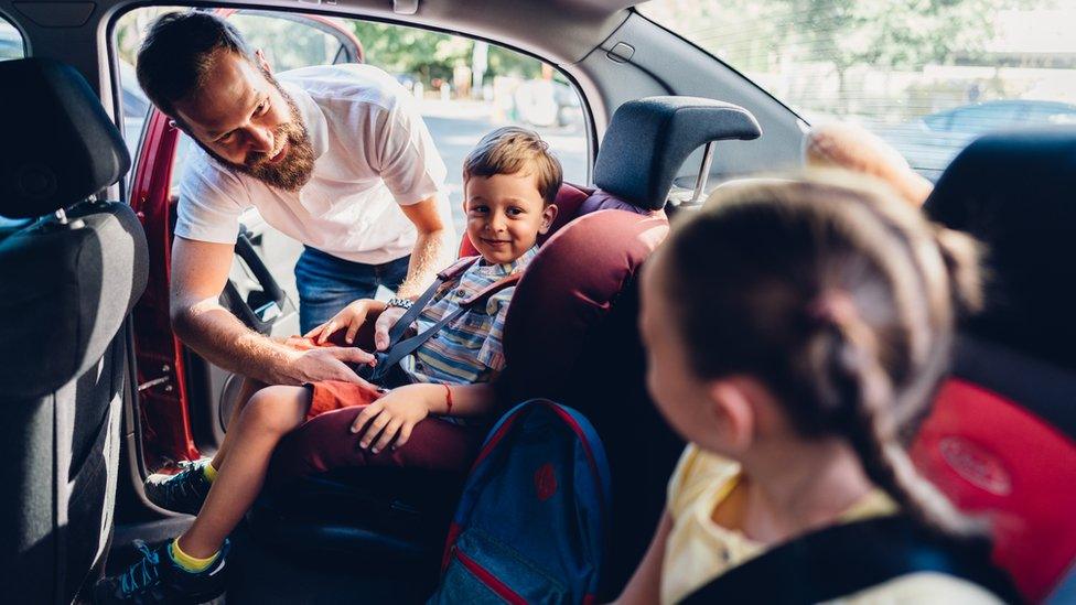 A man putting his children into car seats