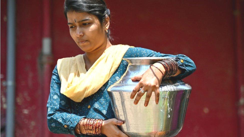 A woman carries a can of water filled from a municipal tap, amid an ongoing water crisis in Bengaluru on March 7, 2024.