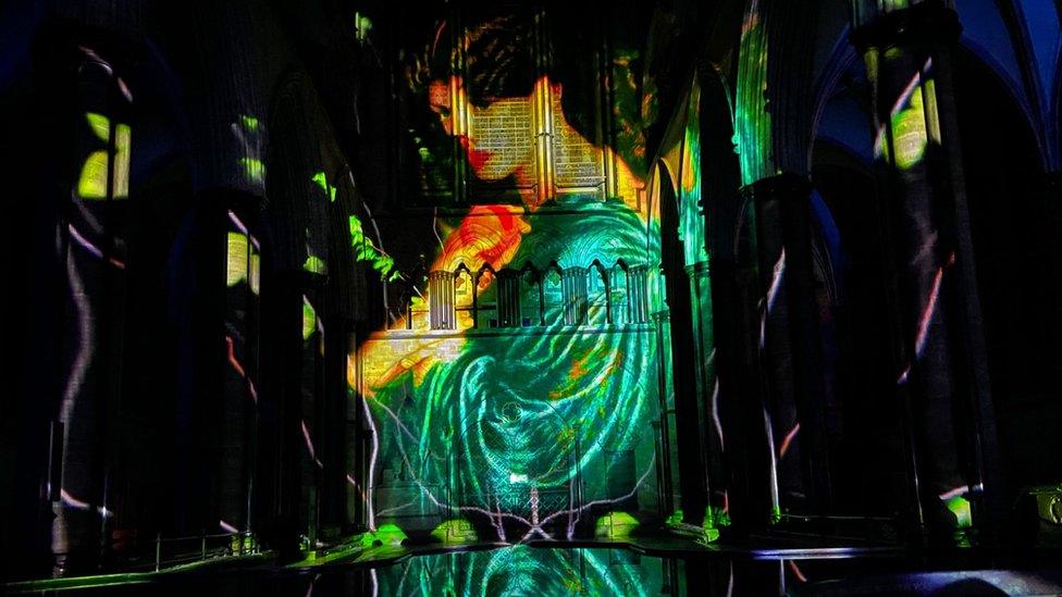 Projection of a woman with a green dress onto a wall