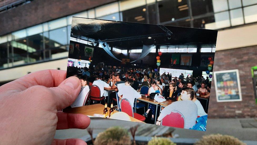 Julie holds a picture of people in a venue