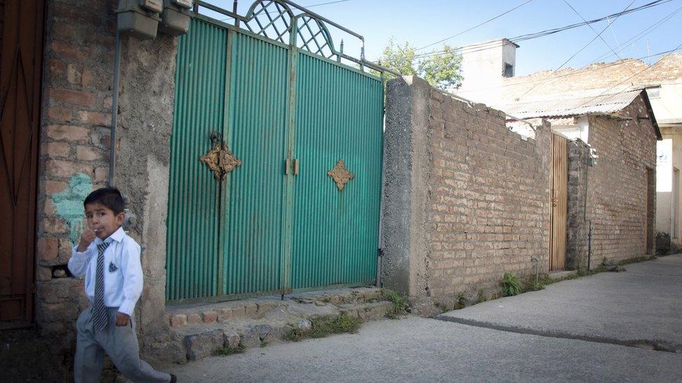 A school boy walks past the gates of Shakil Rafiq's home