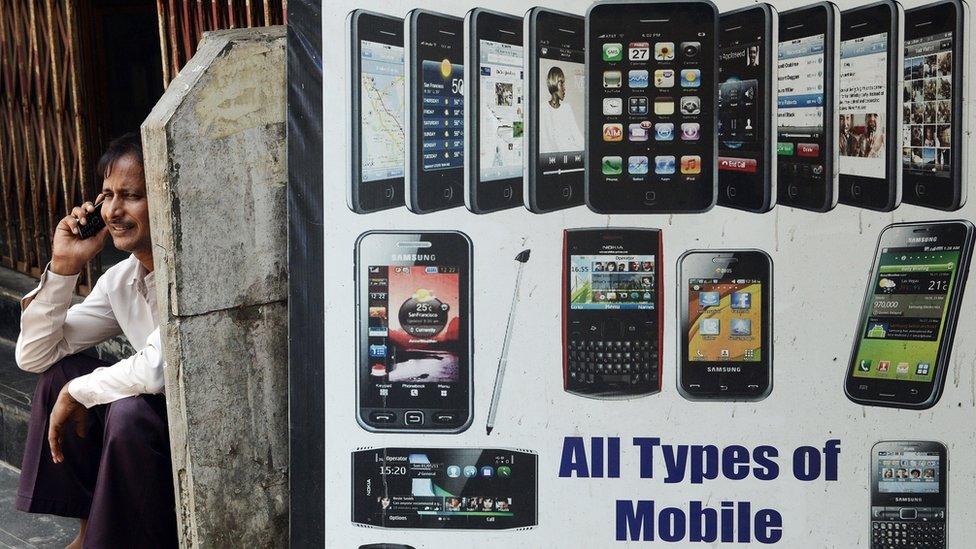 A man talks on his phone outside a shop selling mobile devices