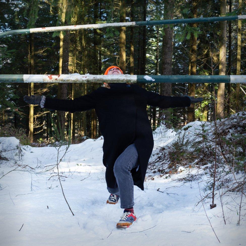 An image of a woman limboing a pole in a snow-covered forest