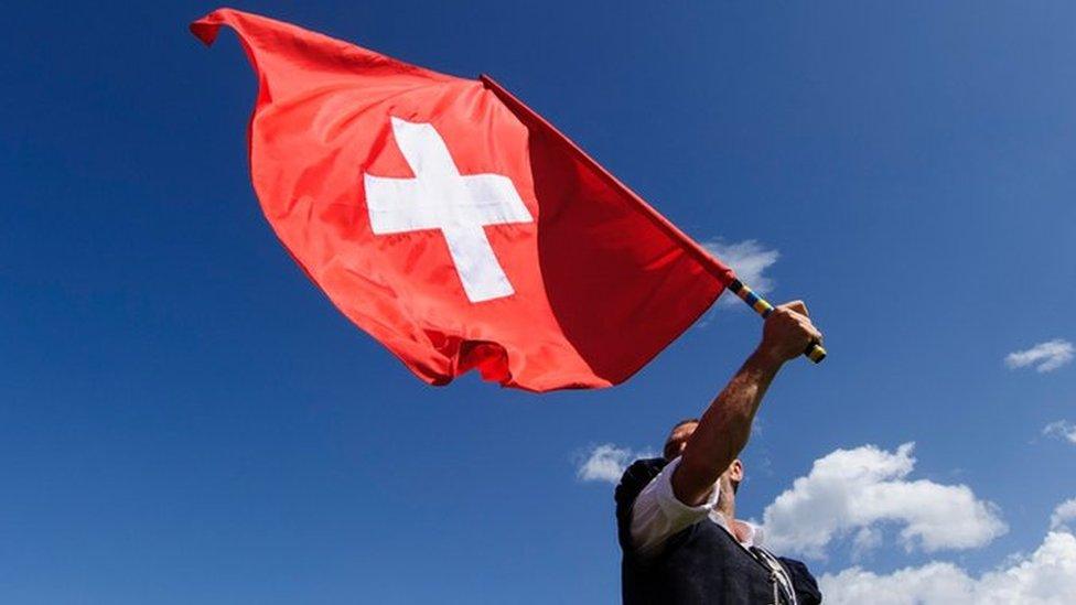 A man throws a Swiss flag on July 28, 2013 in Nendaz, Switzerland