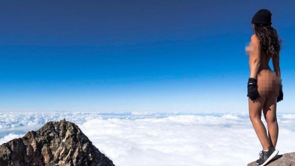 Naked woman on top of a mountain