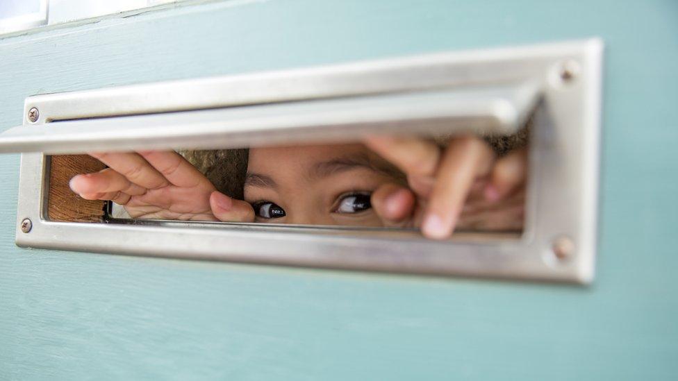 Child peeking through letterbox