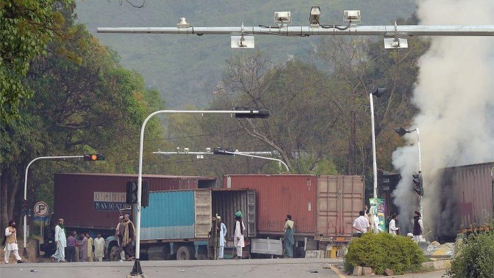 Protesters stand by burning trucks in Islamabad, Pakistan (28 March 2016)