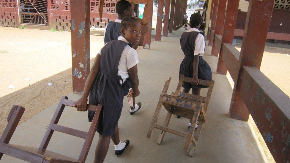 Children dragging chairs to calss