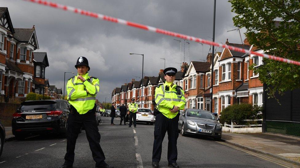 Police officers on street behind police tape