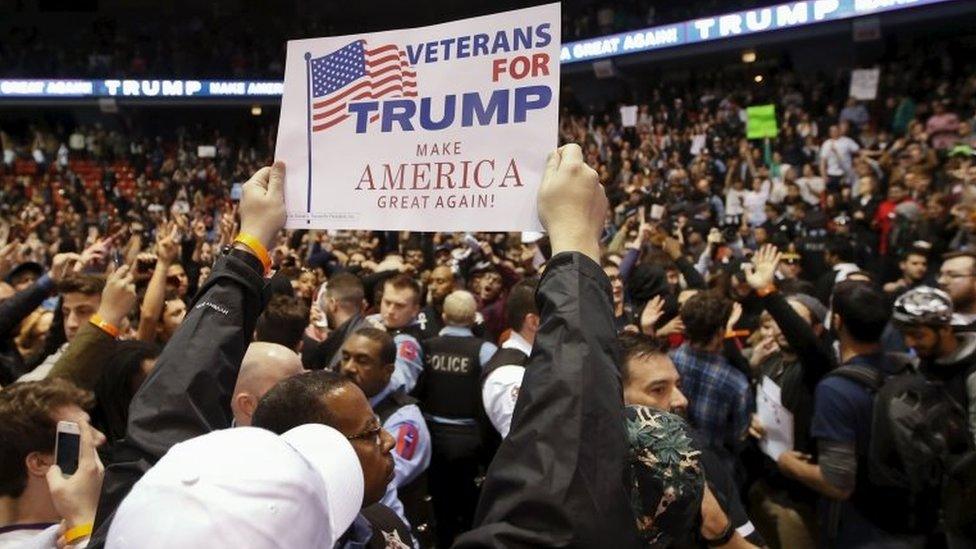 A Trump supporter holds a sign against demonstrators after Republican US presidential candidate Donald Trump