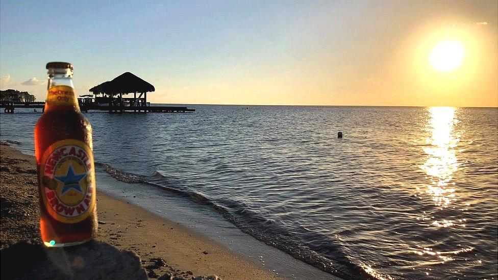 A bottle of Newcastle Brown Ale on a beach on Honduras