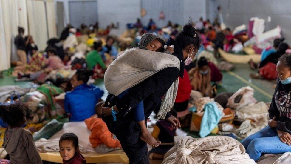 A woman carries a baby at a shelter for displaced people