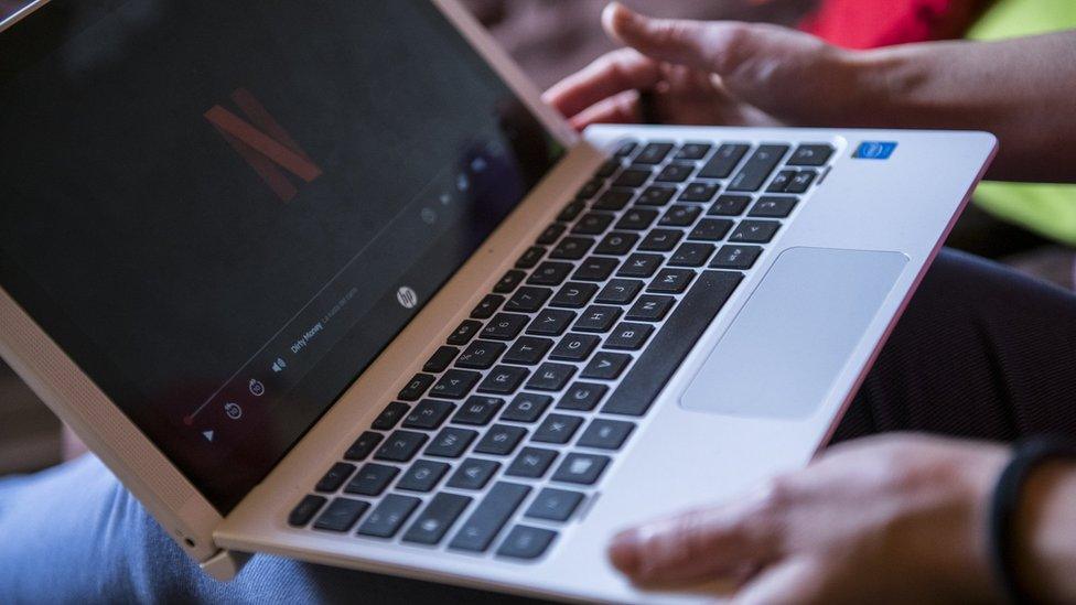 a woman watches netflix on her laptop