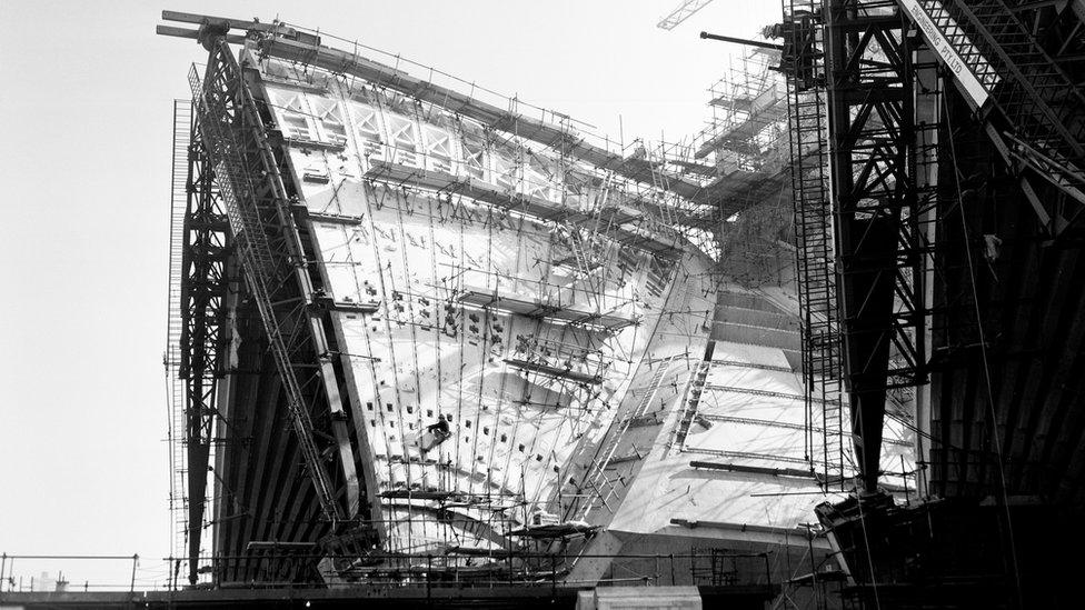 A construction worker scales the roof of the Opera House in 1965