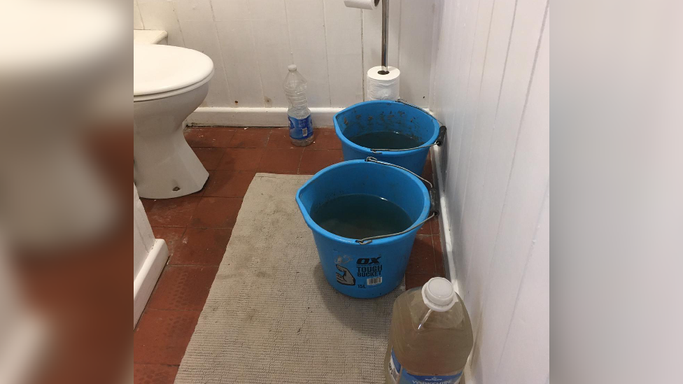 Buckets of water next to toilet