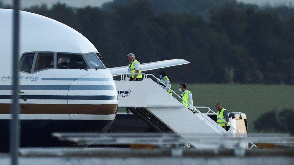 Members of the staff board a plane that was set to transport migrants to Rwanda