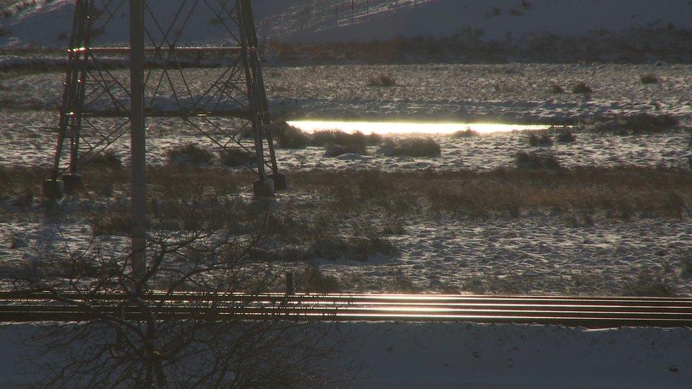 Railway lines and power lines run through the wild landscape