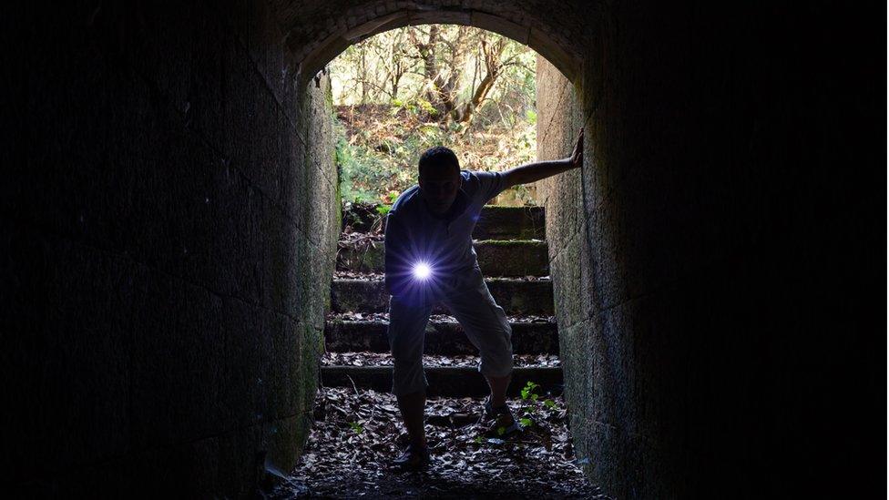 Man searching dark vault with torch