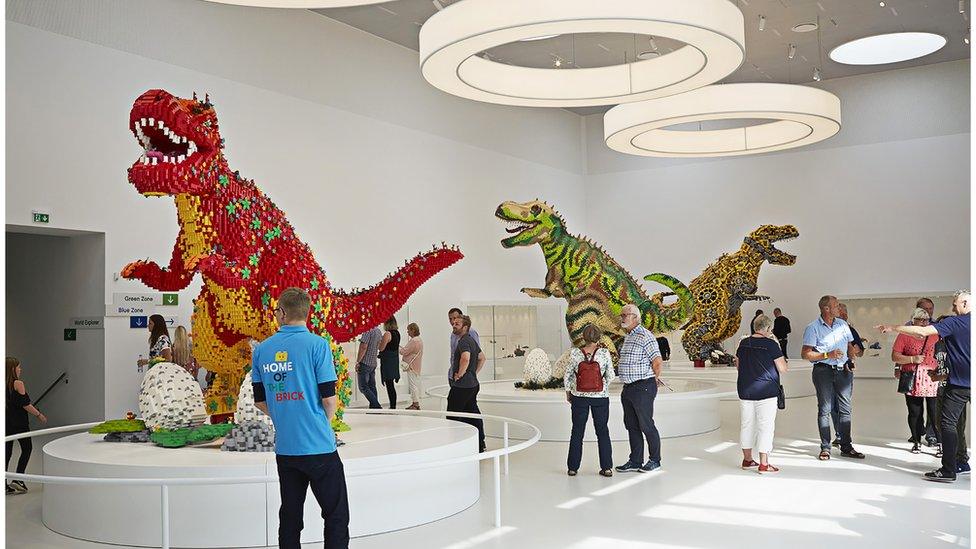 People look at dinosaurs in the Masterpiece Gallery at Lego House