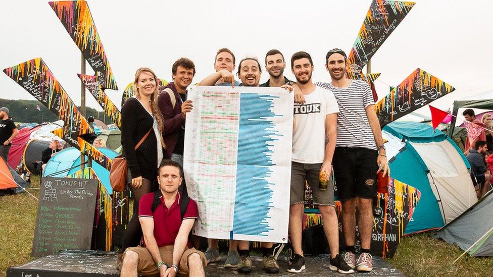 People hold a giant spreadsheet at a festival