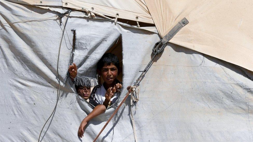 Syrian children look out of a hole in their tent in Zaatari refugee camp, in the Jordanian city of Mafraq