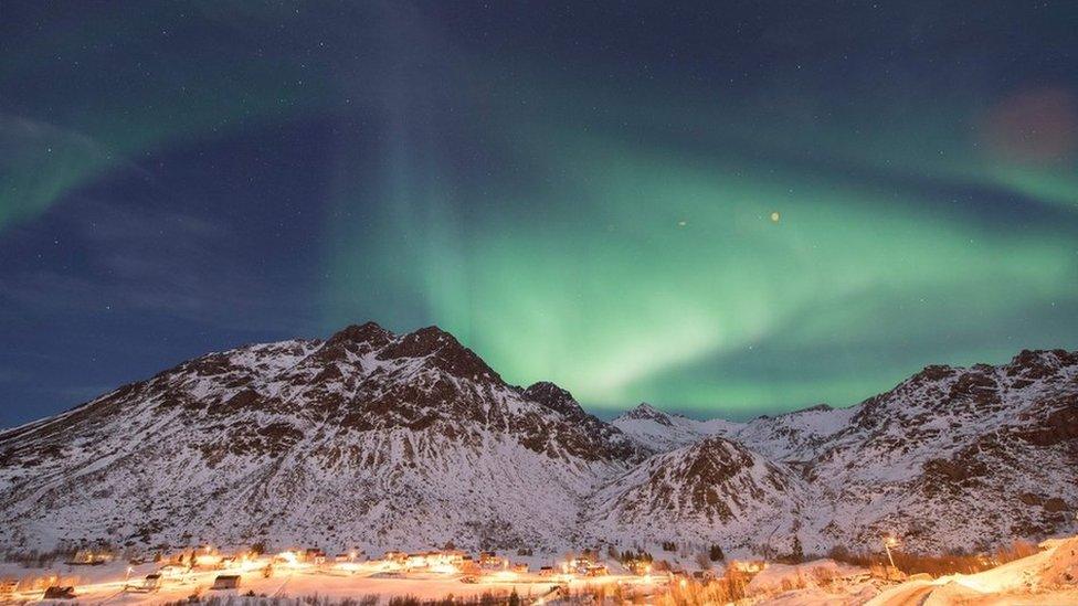 Mountains with northern lights and village lights