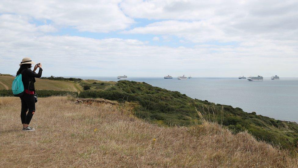 Woman takes a photo of cruise ships in Portland, Dorset