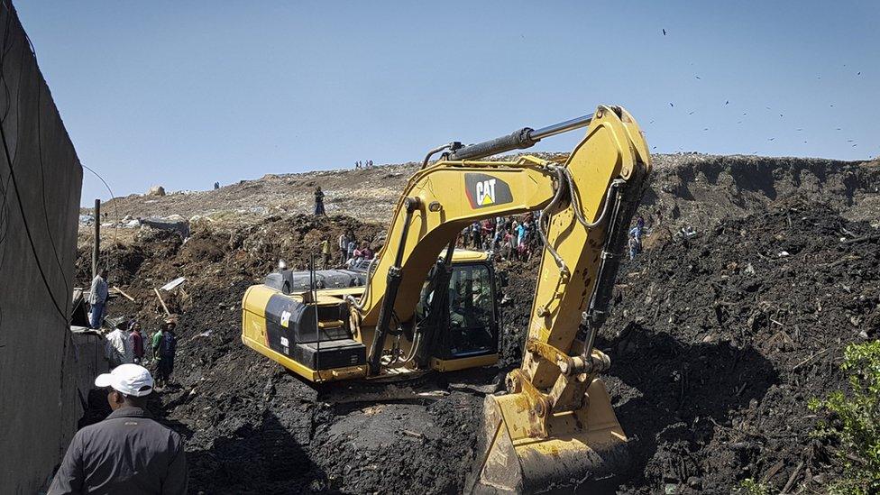 An excavator aids rescue efforts at the scene of a garbage landslide