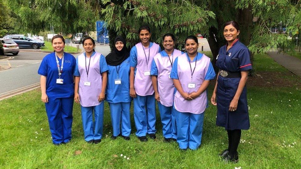 group of nurses standing in front of a tree