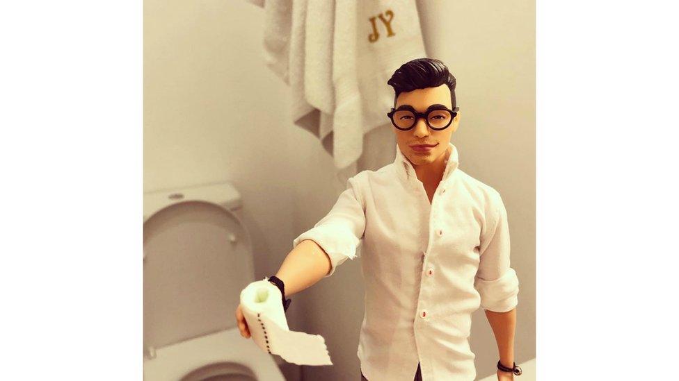 A male doll holding a toilet roll