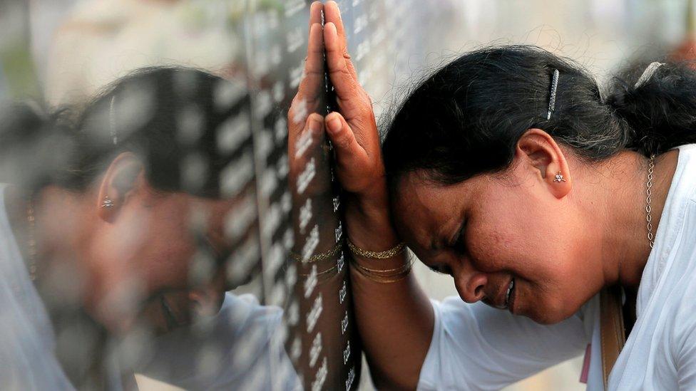 A family member of a Sri Lankan soldier who died in the civil war cries in front of a memorial