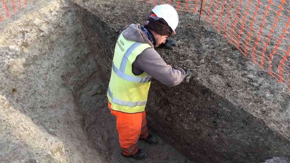 An archaeologist standing in a pit