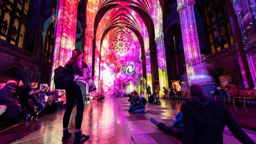 A photo of spectators viewing the light show projections on the wall