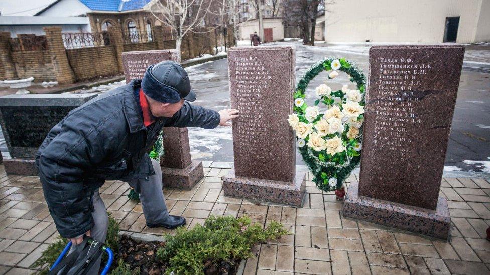 Man looking at tombstone