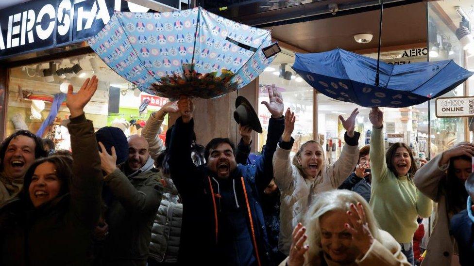 People use umbrellas to collect sweets and gifts thrown to them from floats by people dressed as the Three Wise Men in Ronda, Spain January 5, 2024