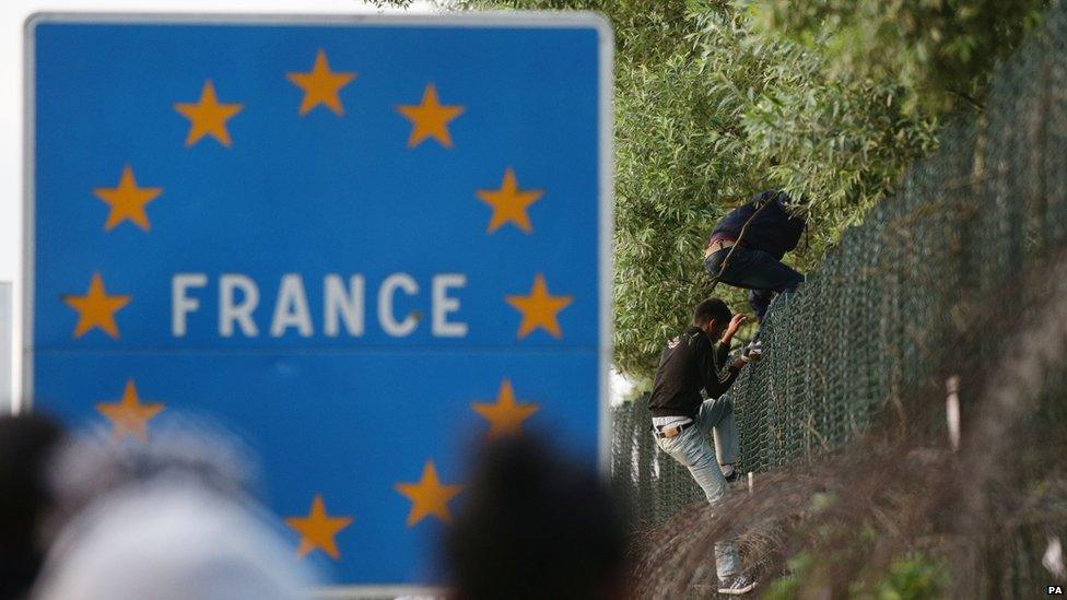 Migrants climb the perimeter fence of the Eurotunnel site at Coquelles in Calais, France