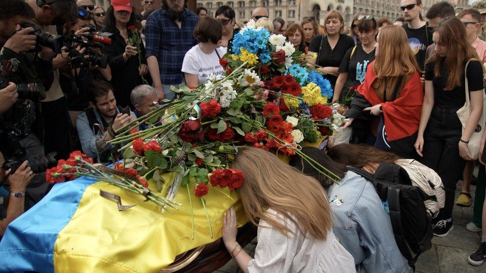 Mourners pay their respects and leave flowers on the coffin of Roman Ratushny in Independence Square