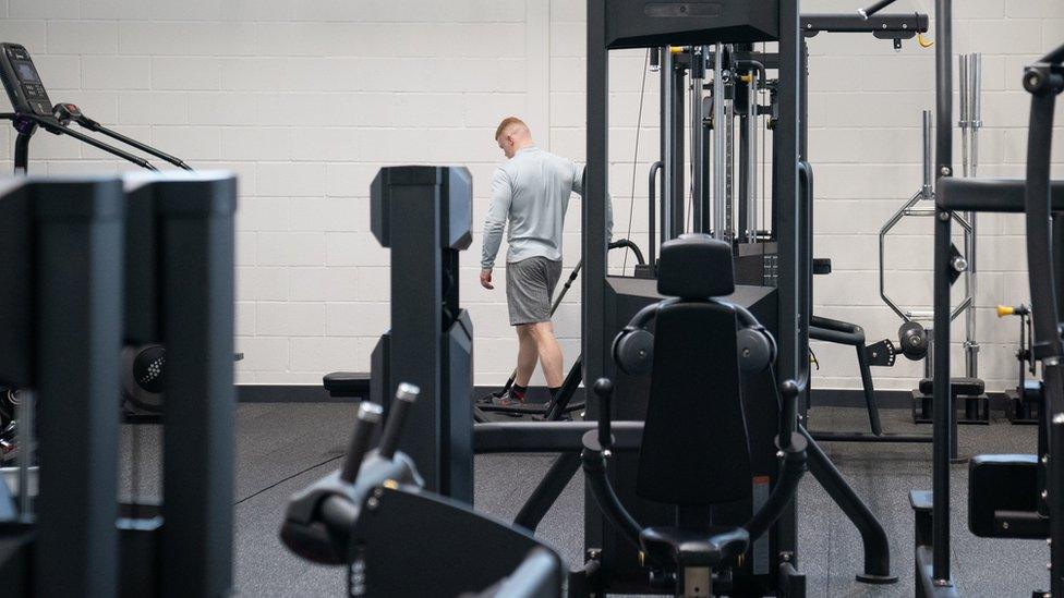 An offender vacuums the gym at category C prison HMP Five Wells in Wellingborough