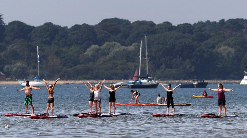 People standing up on paddleboards during an exercise class at Poole in Dorset