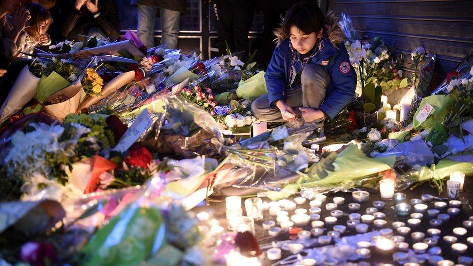 A young boy looks at floral tributes laid near a restaurant targeted in one of the attacks