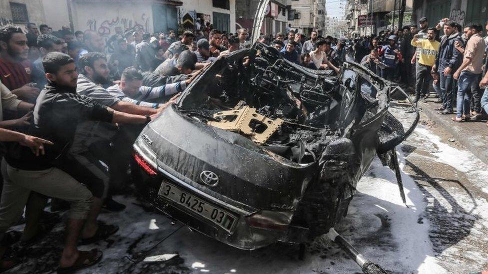 Palestinian emergency personnel try to put out the fire on a car