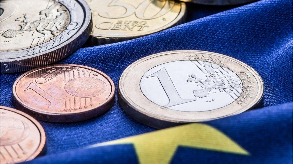 Euro coins pictured on a European flag