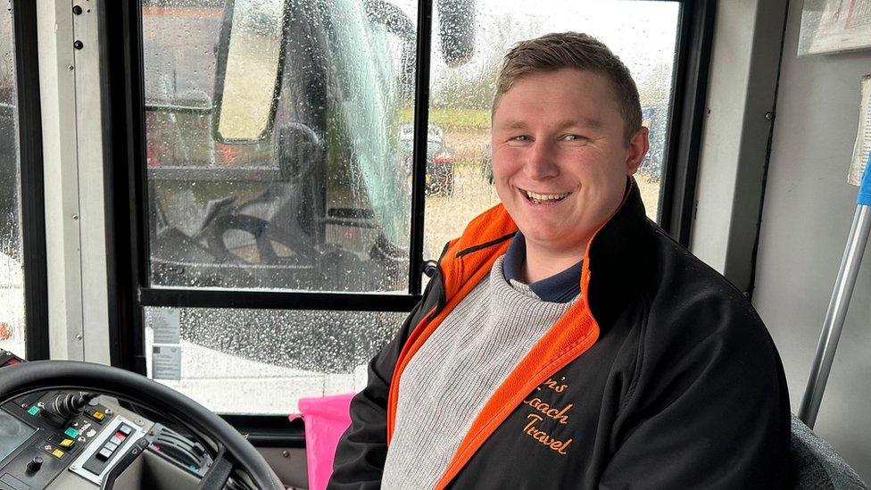 The owner of Dan's Coach Travel, Dan Trent sitting on a bus