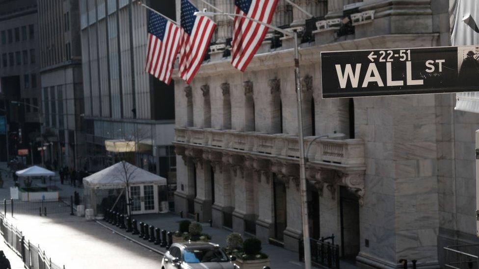 New York Stock exchange with Wall Street street sign in foreground.